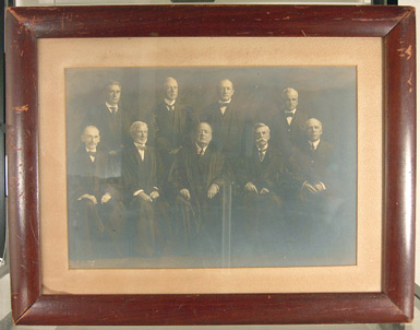 , - Photograph of the Court, the frame measuring some 14 x 18 inches, the image 9 x 13 inches, a formal pose, all of the justices in their judicial robes, five standing with four behind, with the embossed stamp of Harris & Ewing in the lower left-hand corner